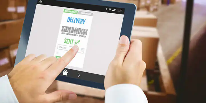 Man using tablet pc against warehouse with cardboard boxes